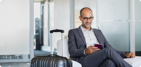 Man sitting at airport with suitcase