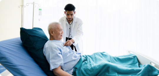 Doctor using stethoscope to check an elderly patient in a hospital bed