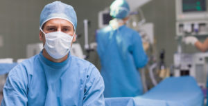 Doctor wearing scrubs and surgical mask in patient room